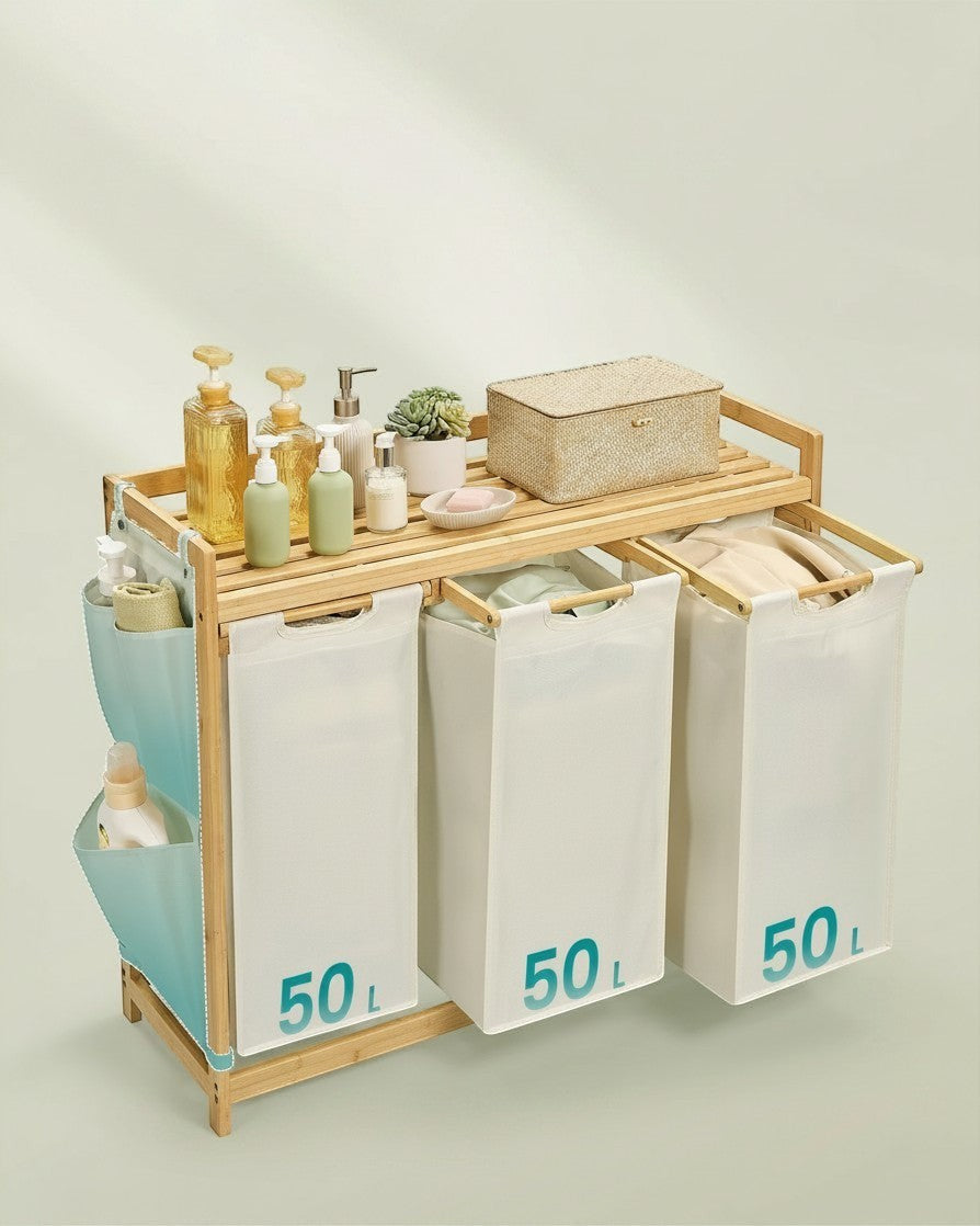 Tokari bamboe wasmand met drie witte 50L waszakken en zijvakken voor extra opbergruimte in een lichte kamer.