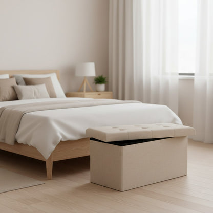 Tokari opvouwbare opbergpoef in beige stof met gecapitonneerde zitting aan het voeteneind van een bed in slaapkamer