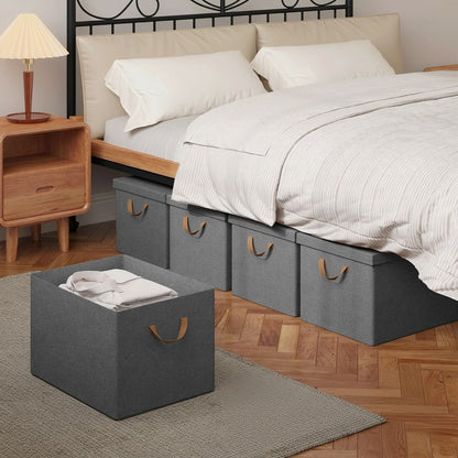 Tokari opvouwbare grijze opbergboxen met deksel en bruine handvatten, geplaatst onder een bed in een slaapkamer.