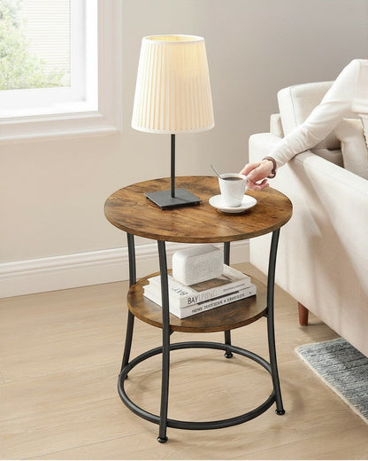 Tokari ronde bijzettafel met twee niveaus, bruin houtlook blad en zwart stalen frame naast een bank.