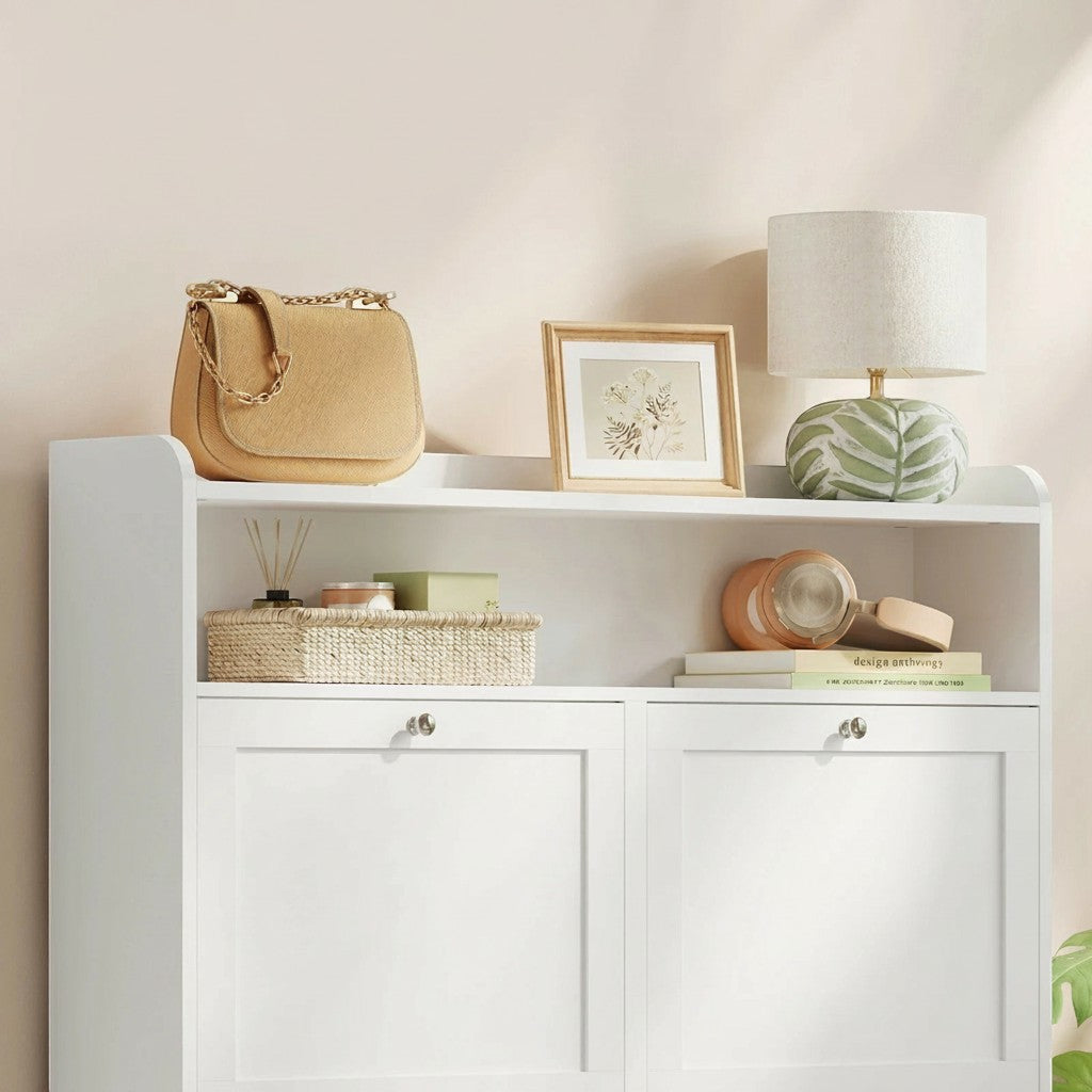 Tokari smalle witte schoenenkast met vier lades, open opbergplank en decoratieve accessoires op het bovenblad.