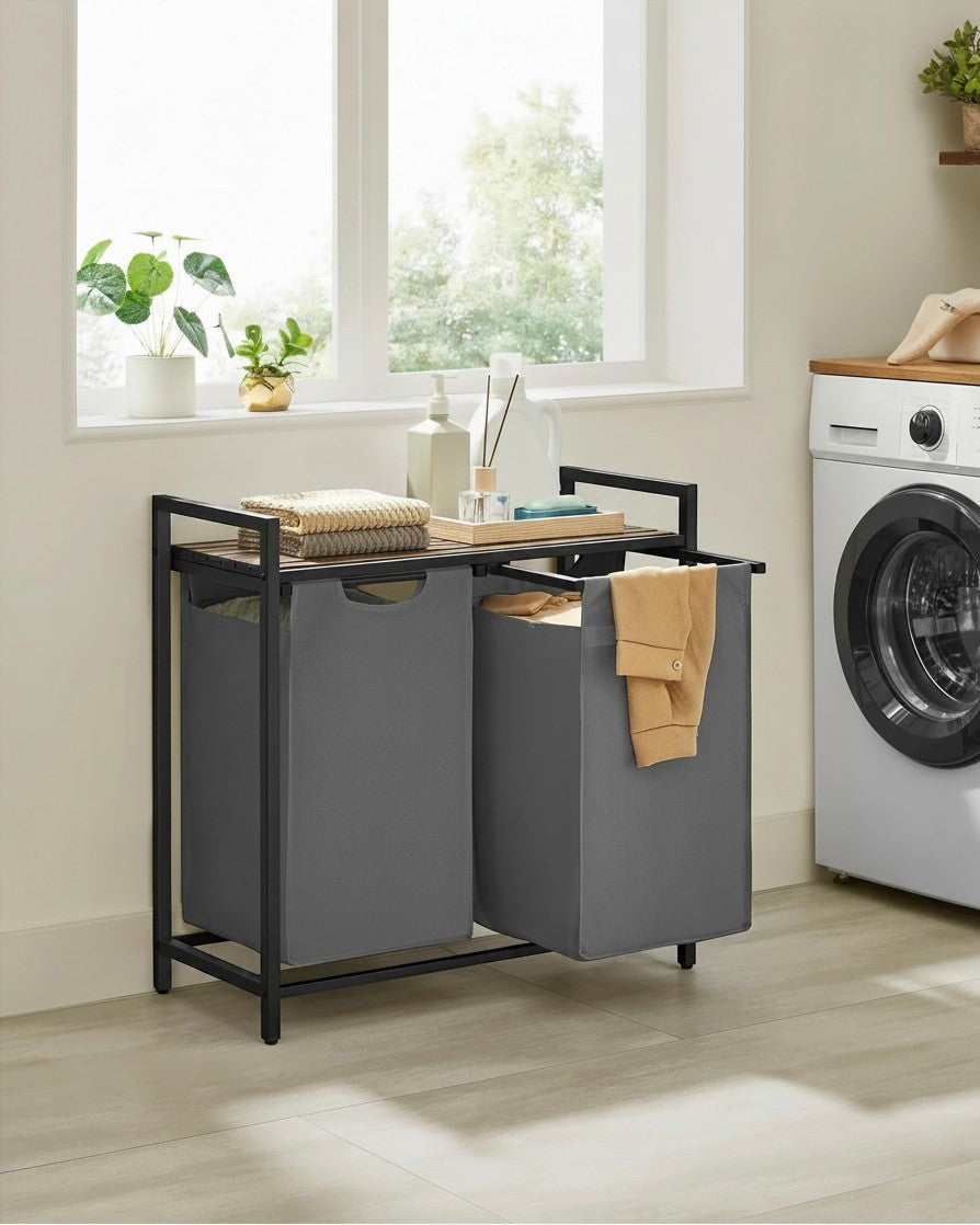 Tokari wasmand met 2 grijze stoffen waszakken, zwart metalen frame en houten bovenblad voor badkamer of wasruimte.