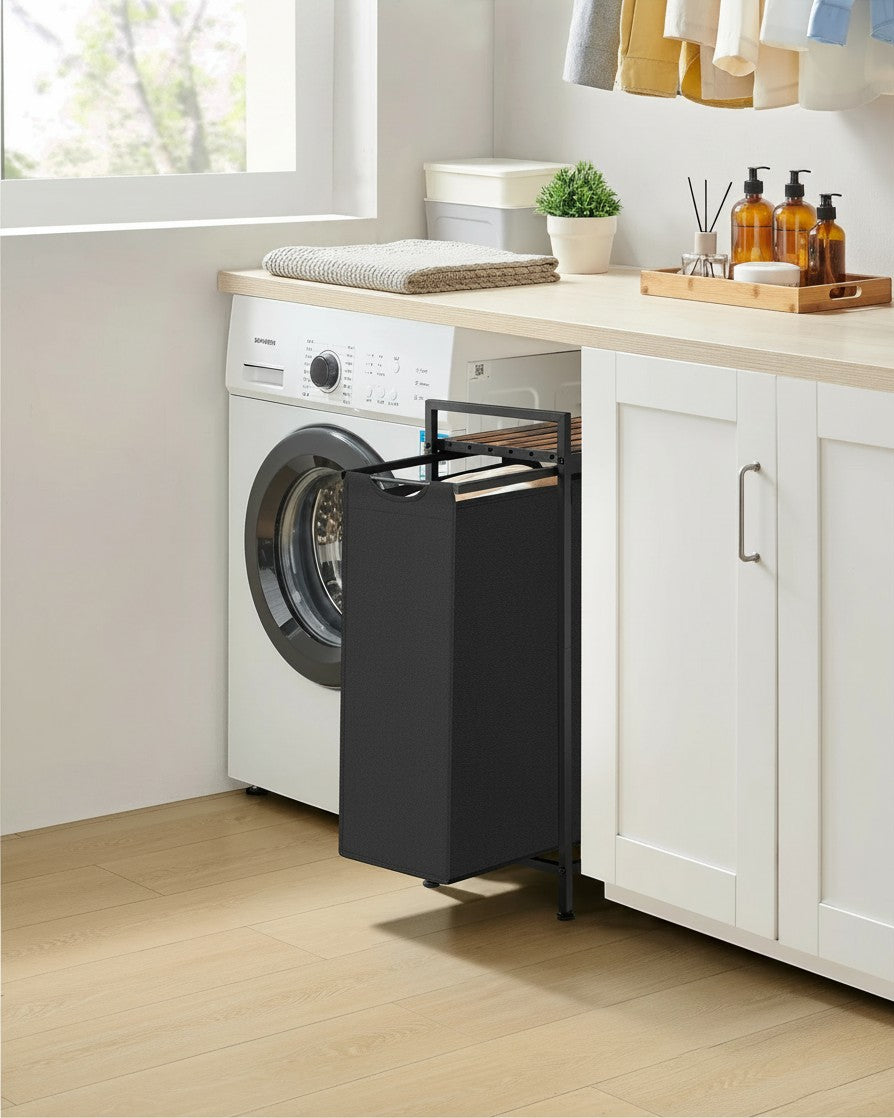 Tokari wasmand in zwart met houten bovenblad, geplaatst in een moderne badkamer naast een wasmachine.